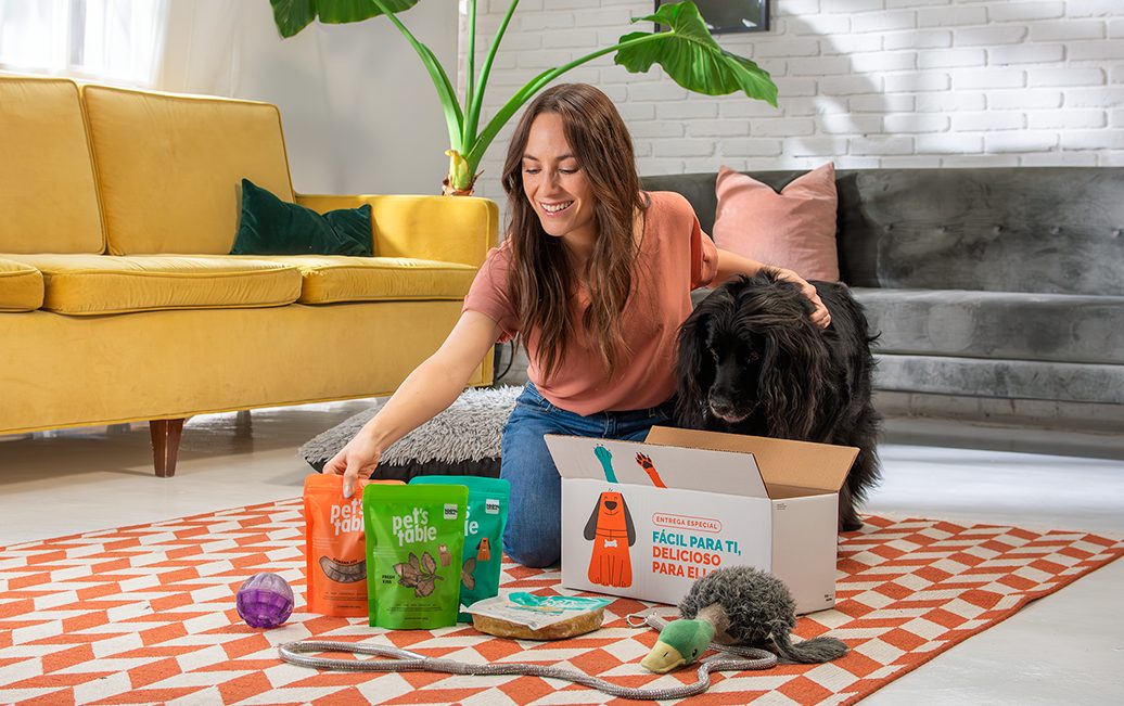 Mujer abriendo una caja de Pet’s Table junto a su perro